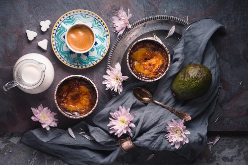 Still life with creme brulee , avocado and cup of coffee on the stone background top view
